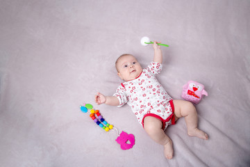 Naklejka premium Baby girl smiling around baby toys