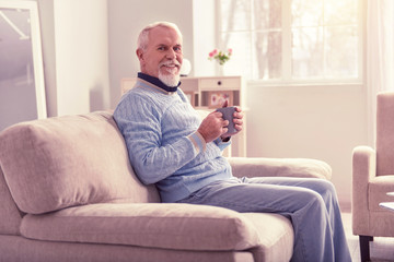 Beaming pensioner carrying cup of morning coffee