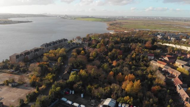 Flying over a small forest in Purfleet revealing the colors of autumn and London skyline in the distance