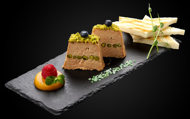 Terrine of Foie Gras with pistachio nuts on a dark background © GrumJum
