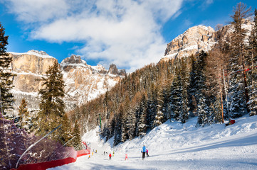 Skiers skiing down the slope in Val Di Fassa ski resort in Dolomites, Italy.