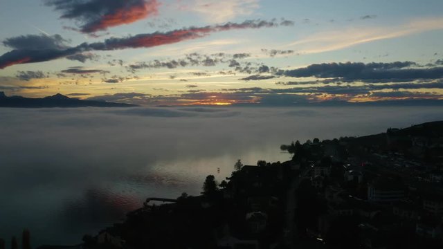 Aerial passing over lake shore and descending towards fog patches reflecting in the water at sunset
Cully, Lavaux - Switzerland