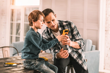 Interested father showing his son some cool functions of his tool.
