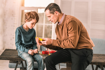 Dedicated passionate adult man showcasing a really cool device to his young son.