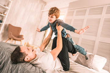 Loving parent carefully holding up his child above him.