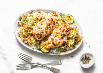 Dijon baked chicken with rice, courgettes and fried onions on light background, top view