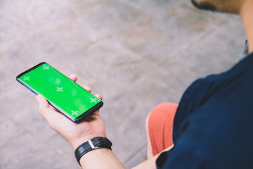 hands holding touching mobile phone with blank copy space on green screen for your text message Selective focus