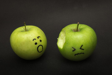 two apples with faces one sad and bitten second is terrified