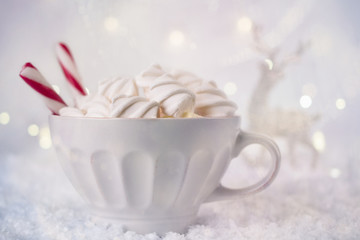 Fototapeta na wymiar Hot Coffee cup with marshmallows and red candy cane on a frosty winter background. Christmas holidays background. Copy space for text.