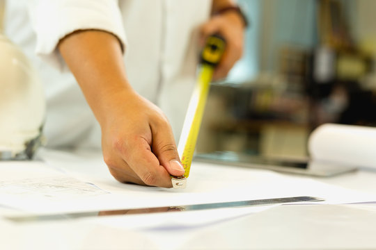 Architecture hand measuring blueprint with tape masure on working table.