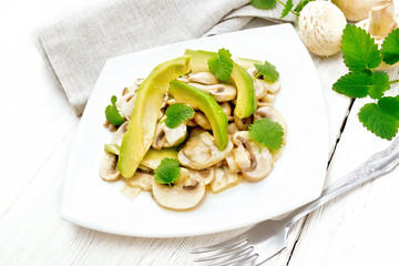 Salad of avocado and champignons on light board