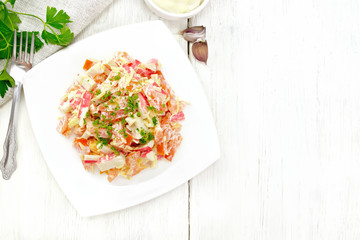 Salad of surimi and tomatoes with mayonnaise on wooden board top