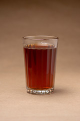 Glass with black tea on a brown background