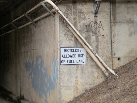 Bicyclists allowed use of full lane sign posted on street tunnel leading to dark area