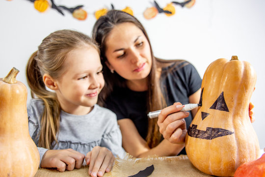A mother and her daughter carving pumpkin together