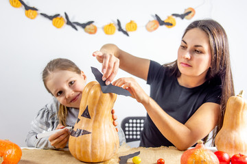 A mother and her daughter carving pumpkin together