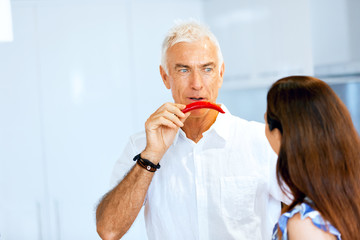 Man holding a red pepper next to his face