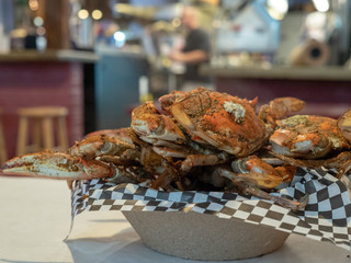 Steamed Chesapeake Bay blue crabs covered in seasoning sitting in paper bowl on paper covered table...