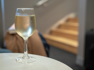 Full glass of white wine sitting on table inside a airport lounge