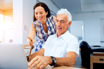 Happy modern mature couple working on laptop at home