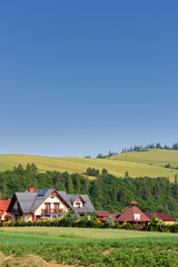 Fototapeta na wymiar Modern, beautiful highlander house at the foot of the mountains, in the distance hills, meadows and pastures, Beskid Niski, Poland