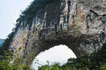 Mountaineer climbing the Moon hill, the famous karst hill in Yangshuo county in Guangxi autonomous region in China near Yangshou, Guilin and Guangxi. Selective focus