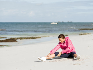 Fototapeta na wymiar Young woman at the beach doing exercises