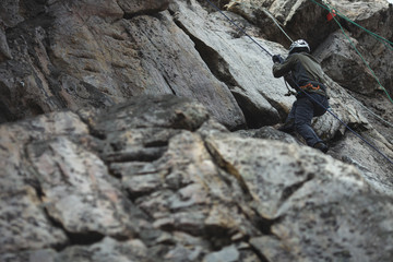 Climber pulls on the rock wall on a safety rope during competitions in sport climbing.