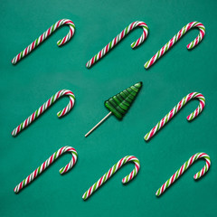 Christmas candy cane in row on green background. Flat lay. Square image. Pattern.