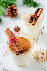 Eggnog Traditional Christmas drink milkshake with cinnamon on light old background. Selective focus.