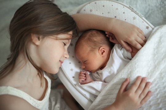 Sleeping children, sister embrace newborn baby