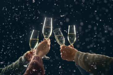 Hands with wine glasses in winter night.