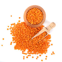 Red lentils in the wooden spoon and bowl, isolated on white background