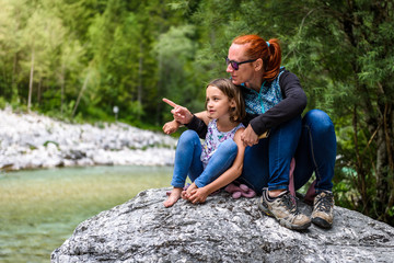 Family sitting on river rock after nature hiking.