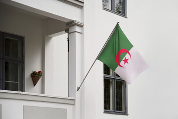 Algeria flag hanging on a pole in front of the house. National flag waving on a home displaying on...