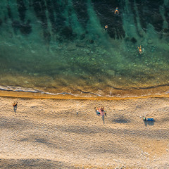 Aerial view from drone of wild sandy beach and people with azure water and seaweed from above, nature background