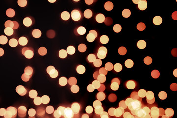 Yellow and orange Christmas tree bokeh on black background of defocused glittering lights, Christmas background pattern concept
