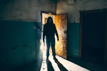 Silhouette of criminal or maniac with knife in hand in old scary building, serial killer with cold...