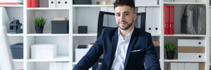 Fototapeta premium A young man sitting in the office at a computer Desk and working with documents.