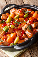 Chicken stew with sweet potatoes, Brussels sprouts in pomegranate sauce close-up in a pan on the table. vertical