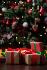 Gifts lie under the tree with a glowing gerland on a dark wooden floor