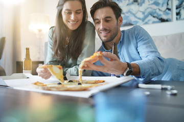Obraz premium Happy relaxed couple sharing a pizza at home