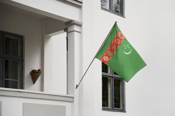 Turkmenistan flag hanging on a pole in front of the house. National flag waving on a home...