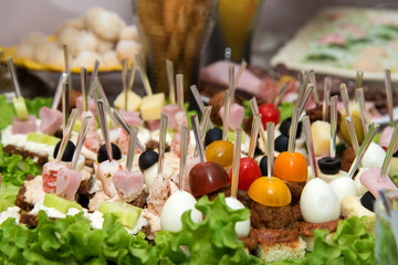 Close up of small canapes arranged on a plate over light background - selective focus