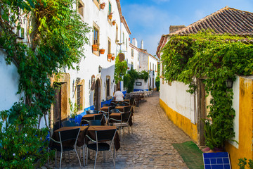 Table and chairs in open air street cafe or restaurant on narrow street of european town