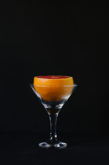 Grapefruit in a martini glass on a black background.