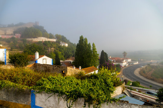 View of the old part of Obidos, Portugal in the early foggy morning - Powered by Adobe