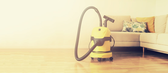 Cleaning service concept. Banner. Yellow vacuum cleaner, sofa on light background with copy space