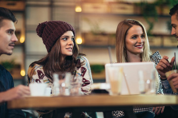 Group of young friends sitting in a coffee shop having fun