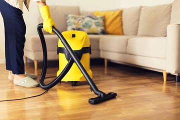 Woman cleaning sofa with yellow vacuum cleaner. Copy space. Cleaning service concept